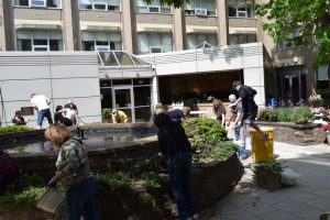 people working on plant garden in front of building