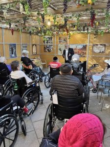 Residents in wheelchairs watch Sukkot services