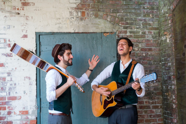 Two members of Pumpidisa standing next to each other playing guitars and singing.