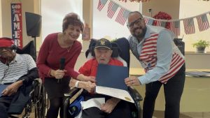 Veteran Jack Alkana proudly wears his U.S. Navy hat in honor of Veterans Day beside Linda Spiegel and Ricardo Sola.