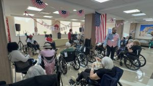 A vibrant scene of a senior event with attendees enjoying a patriotic-themed celebration, complete with American flags and certificates of appreciation for veterans.